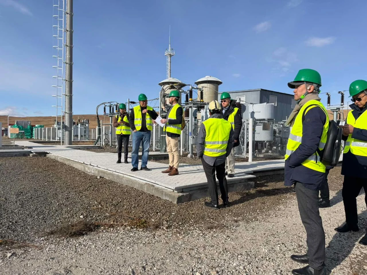 Site visit team in hard hats and safety vests at an electrical substation, Mongolia